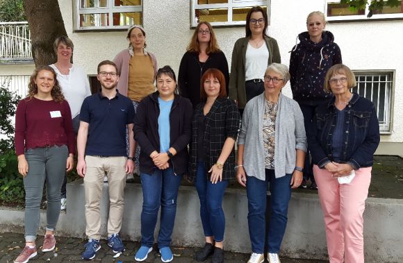 Eine Gruppe von Personen posiert lächelnd für ein Foto, das die erfolgreiche Nachbarschaftshilfe zeigt.